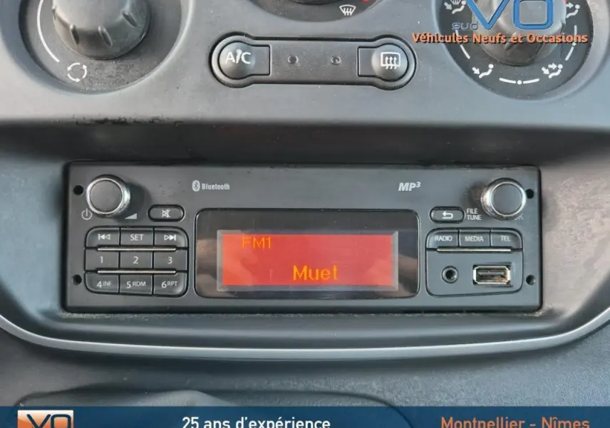 Tableau de bord du Renault Kangoo blanc 2016 montrant la radio Bluetooth et commandes climatisation manuelle.