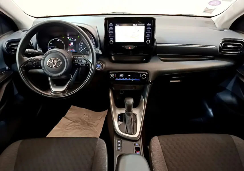 Intérieur de Toyota Yaris hybride 2021, vue frontale du tableau de bord avec écran tactile et volant multifonctions cuir.