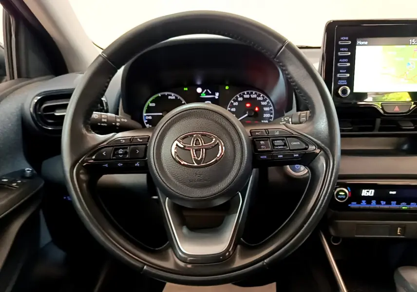 Vue intérieure centrée sur le volant cuir multifonctions d'une Toyota Yaris hybride 2021 avec écran tactile et tableau de bord numérique.