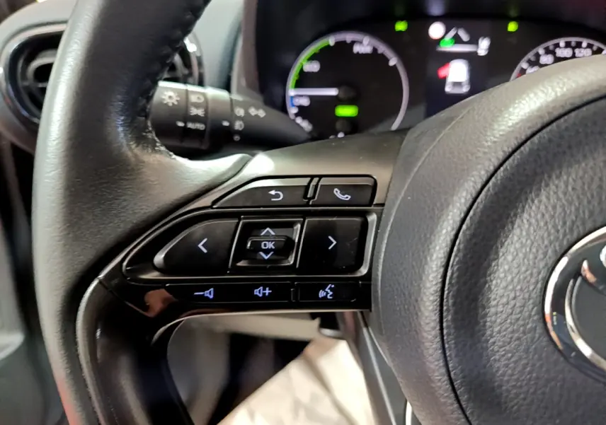 Gros plan sur le volant cuir de la Toyota Yaris hybride 2021, côté gauche avec commandes multifonctions visibles.