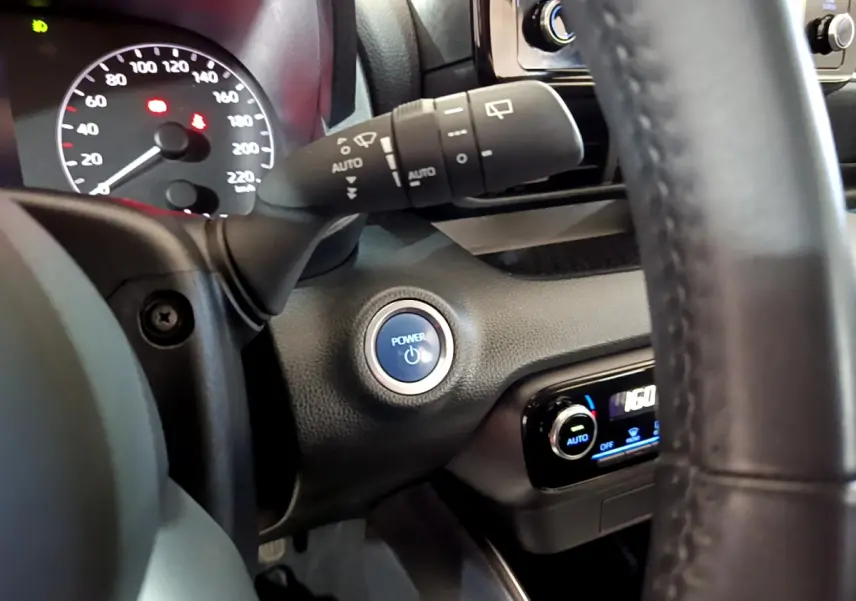 Détail intérieur montrant le bouton Power bleu et le combiné d'instruments de la Toyota Yaris hybride 2021.