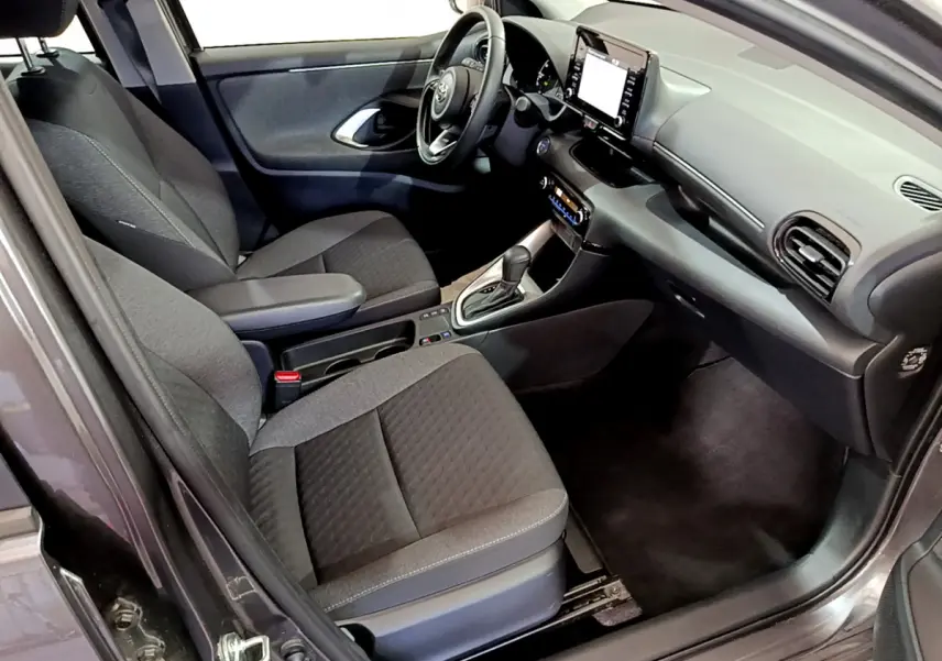 Intérieur avant droit de la Toyota Yaris hybride 2021 gris clair, avec tableau de bord tactile et sièges tissu noirs.