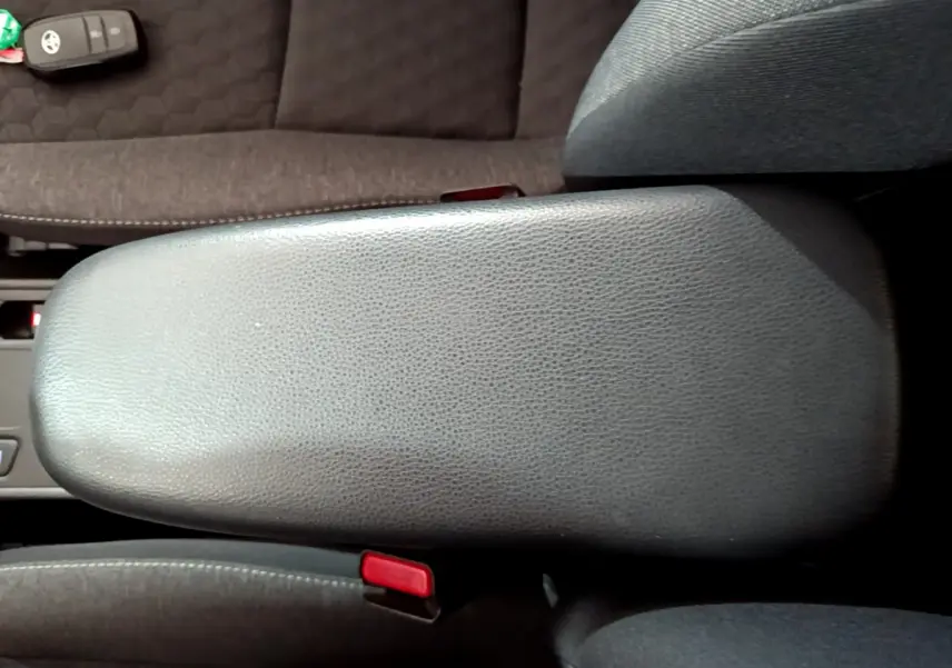 Vue plongeante sur l'accoudoir central en cuir gris et la clé Toyota posée sur le siège tissu foncé d'une Yaris hybride 2021.