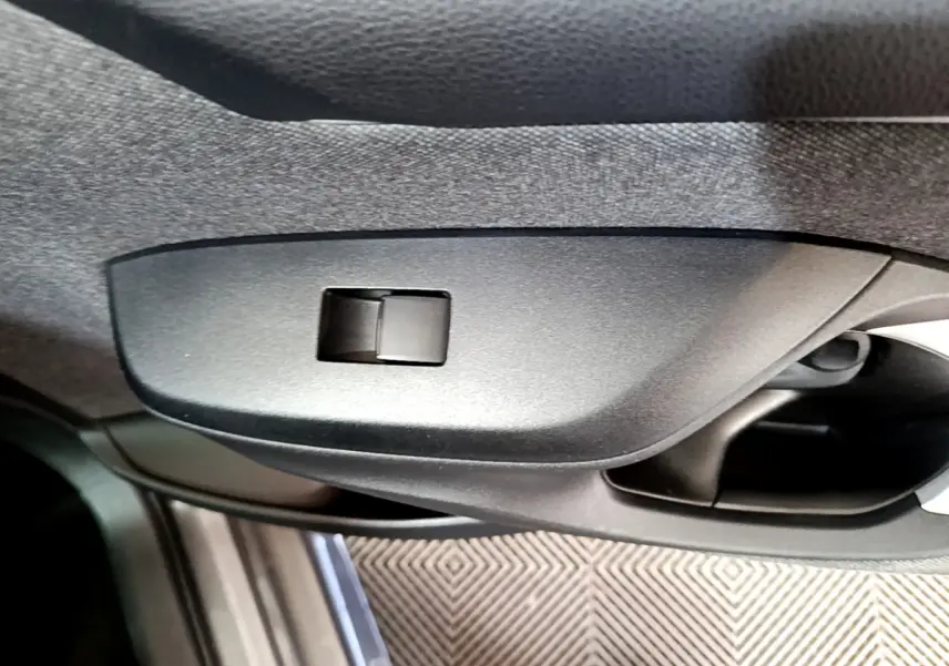 Détail de la commande de vitre côté conducteur dans l’habitacle gris clair de la Toyota Yaris hybride 2021.