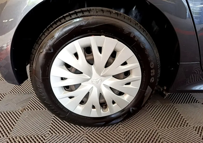 Gros plan sur la roue avant droite gris clair de la Toyota Yaris Hybride 116h avec enjoliveur Toyota distinctif.