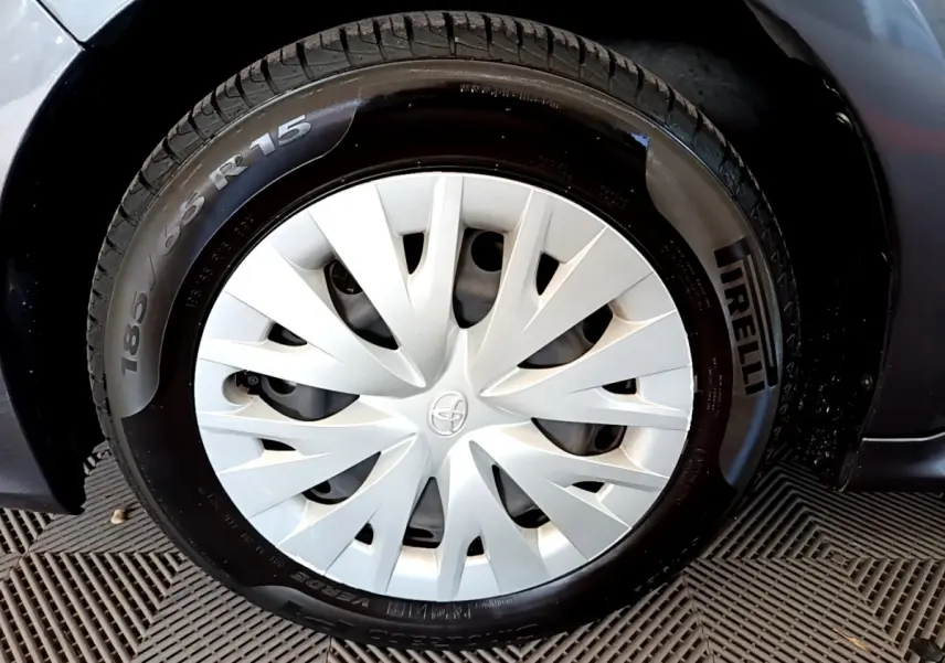 Gros plan sur la roue avant gauche d'une Toyota Yaris hybride gris clair avec enjoliveur blanc et pneu Pirelli.