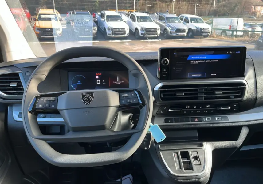 Vue intérieure centrée sur le volant multifonctions et l'écran tactile du tableau de bord du Peugeot Traveller gris titane.
