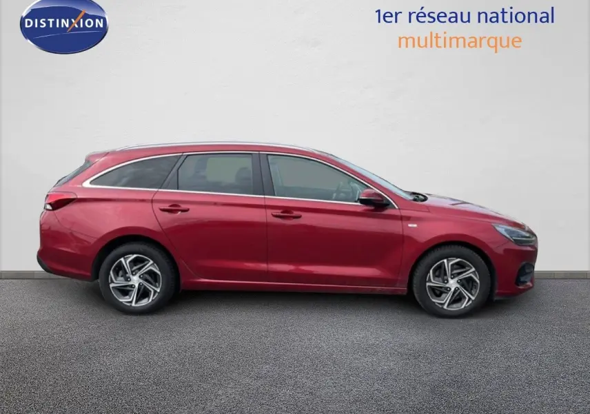 Profil droit d'une Hyundai i30 SW 2023 rouge Sunset Red Metal avec jantes alliage et lignes épurées.