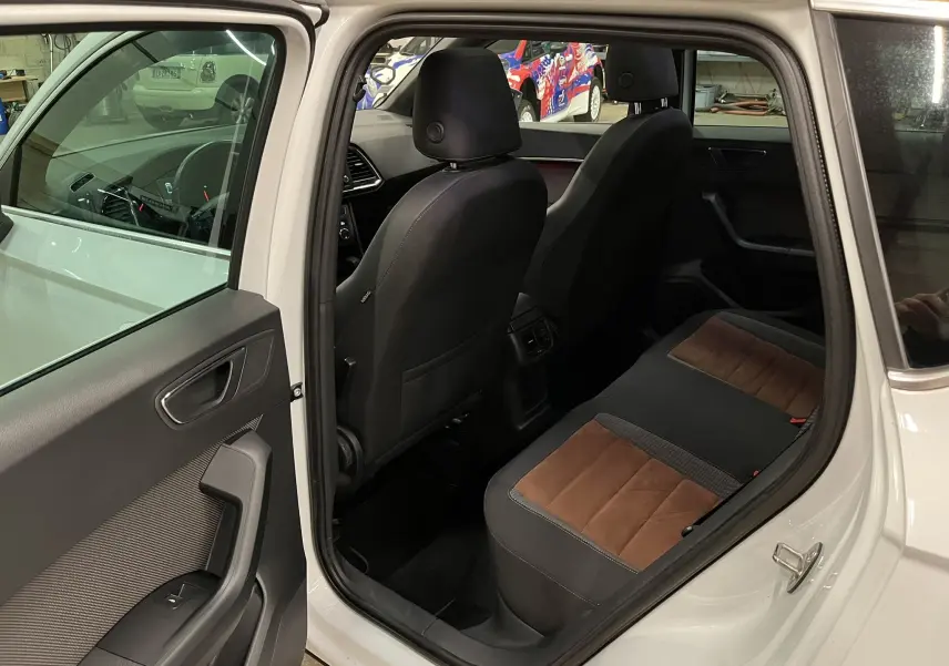 Vue intérieure côté arrière droit du SEAT Ateca blanc 2016, montrant les sièges arrière bi-matière noir et marron.