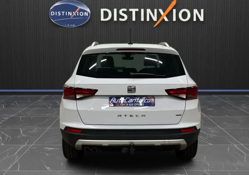 Vue arrière d'un SEAT Ateca blanc 2016 avec attelage et feux arrière allumés en intérieur showroom.