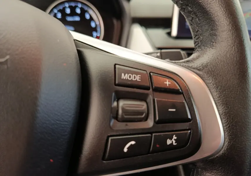 Gros plan sur le volant cuir et alu avec commandes multifonctions du BMW Série 2 Gran Tourer gris clair 218i Lounge.