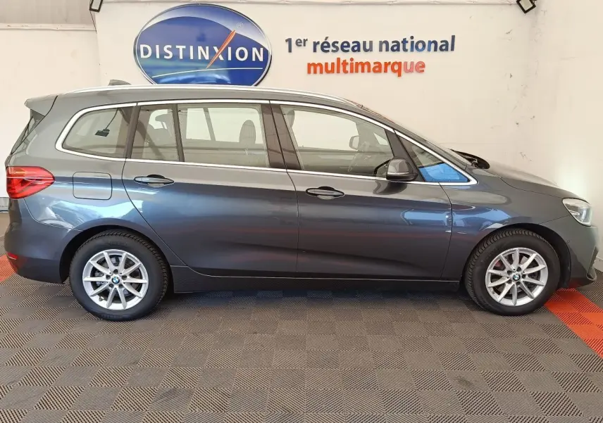 BMW Série 2 Gran Tourer 218i Lounge gris clair vue de profil côté gauche en intérieur showroom.