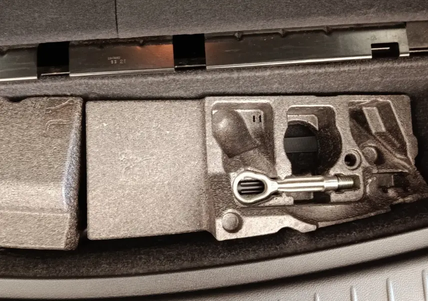 Coffre ouvert montrant le rangement en mousse avec outil de remorquage dans une BMW Série 2 Gran Tourer gris clair.