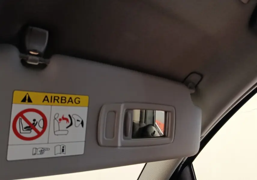 Détail du pare-soleil côté conducteur avec miroir intégré et avertissement airbag dans une BMW Série 2 Gran Tourer gris clair.