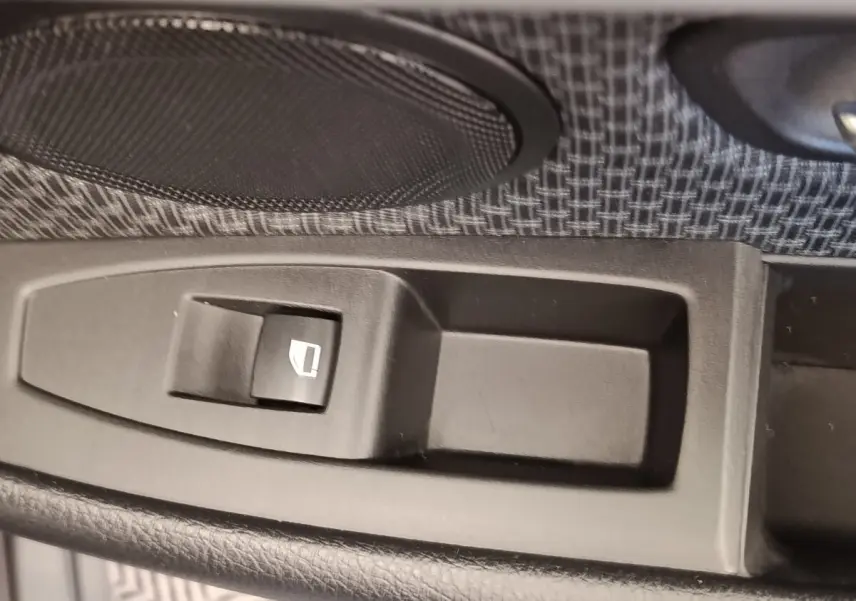 Gros plan sur le bouton de commande électrique de la vitre côté conducteur dans une BMW Série 2 Gran Tourer F46 218i Lounge gris clair.