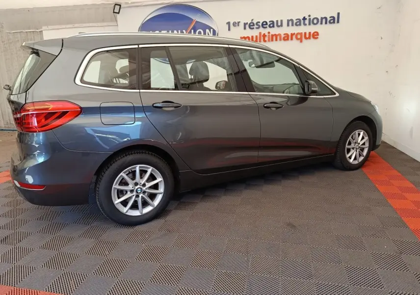 BMW Série 2 Gran Tourer gris clair vue de profil côté droit dans un showroom avec jantes alliage.