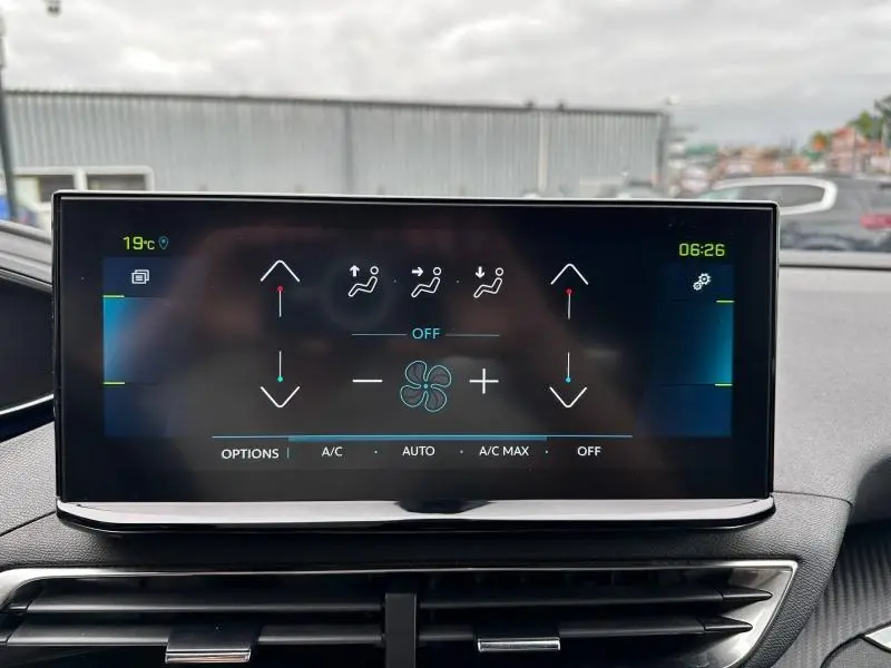 Écran tactile central du tableau de bord du Peugeot 3008 noir Perla Nera, affichant les commandes de climatisation.