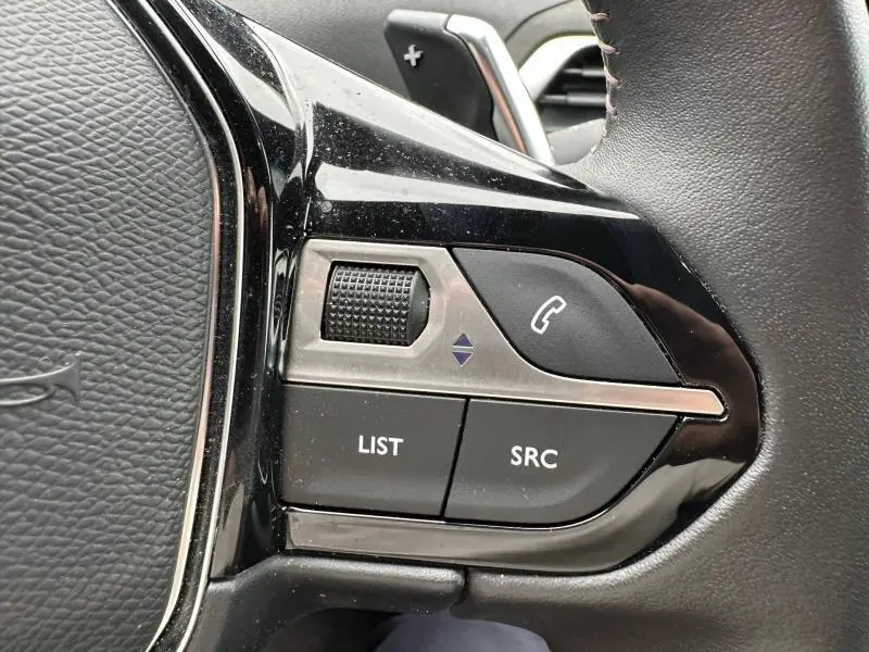 Gros plan sur les commandes noires et argentées du volant cuir du Peugeot 3008 Hybride Rechargeable 2024.