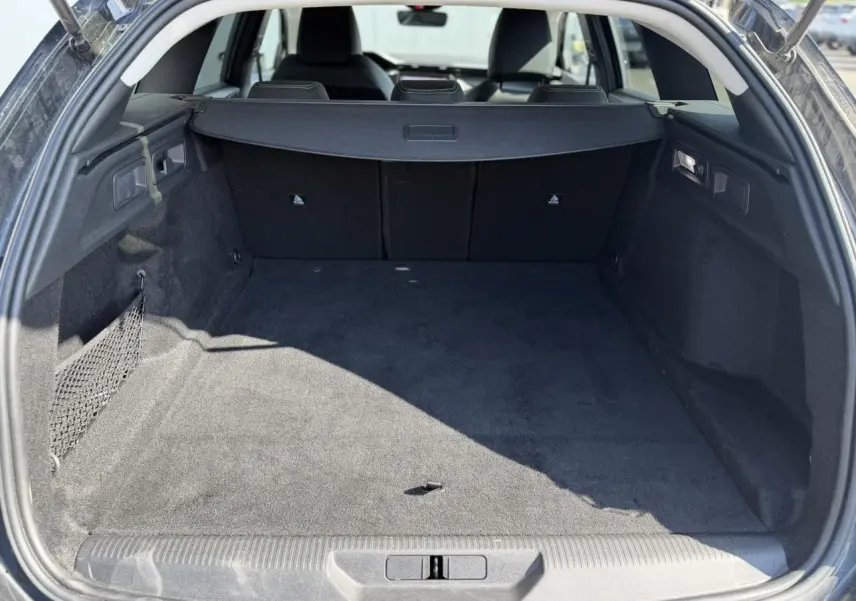 Coffre ouvert vu de l'arrière d'une Peugeot 308 SW noir Perla, espace de chargement spacieux et tapis noir.