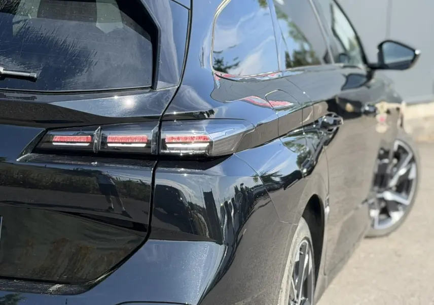 Vue 3/4 arrière droite de la Peugeot 308 SW noire Perla avec feux arrière LED et jantes alliage 17 pouces.