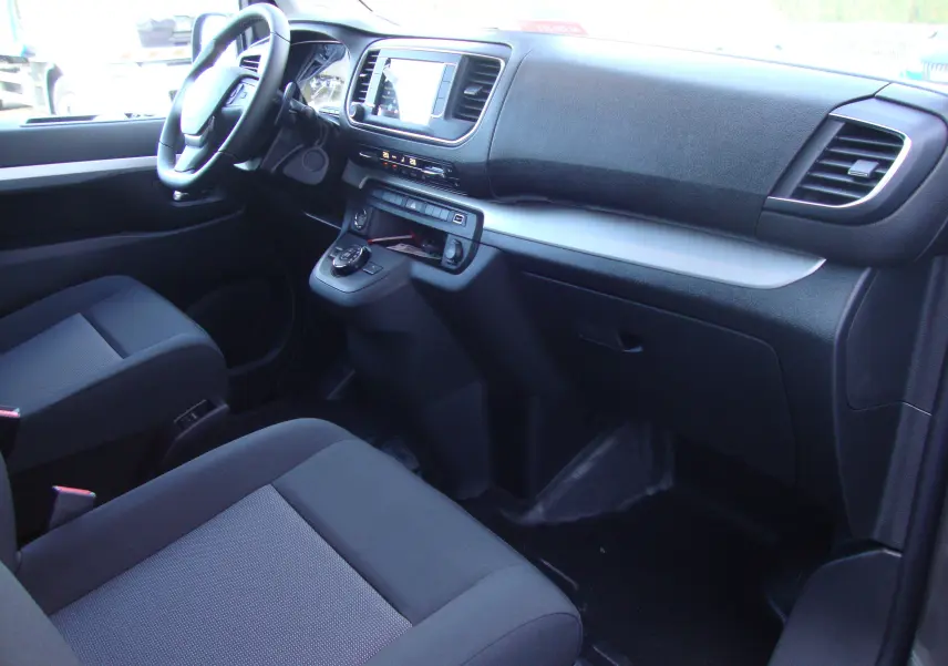Intérieur avant du Citroën Jumpy XL 2024, vue côté passager, sièges noirs et tableau de bord moderne.