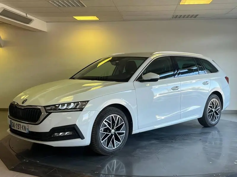 Vue 3/4 avant droite d'une Skoda Octavia Combi blanche Cristal spéciale avec jantes alliage et calandre chromée dans un showroom.
