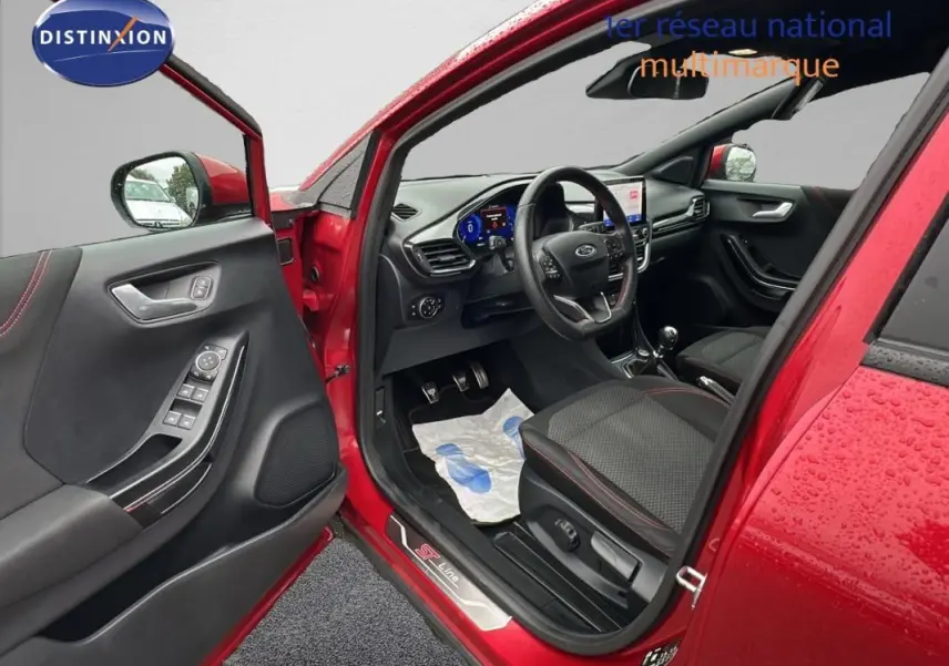 Intérieur côté conducteur d'un Ford Puma rouge 2020, avec sellerie noire et détails ST-Line visibles sur le seuil de porte.