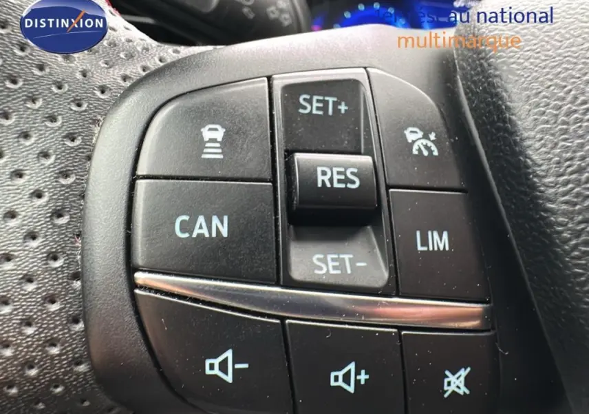 Gros plan sur les commandes au volant de la Ford Puma rouge 2020, mettant en valeur les boutons du régulateur de vitesse et du volume sonore.