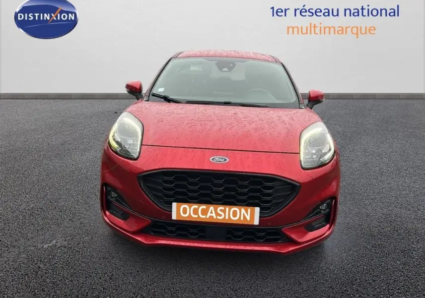 Vue frontale d'une Ford Puma rouge 2020 avec calandre noire et feux allumés sur sol asphalté.