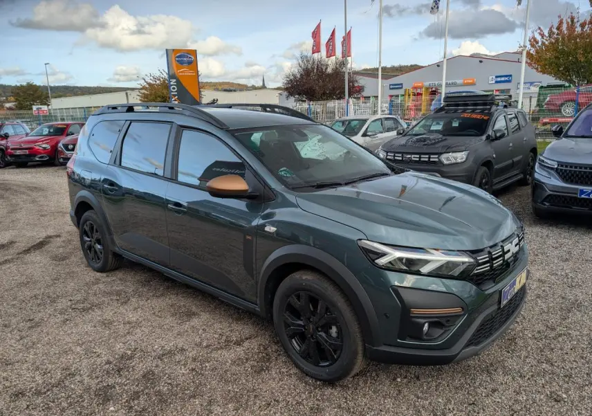 Dacia Jogger 2025 vert métallisé en 3/4 avant droit, avec rétroviseurs brun cuivré et jantes noires.