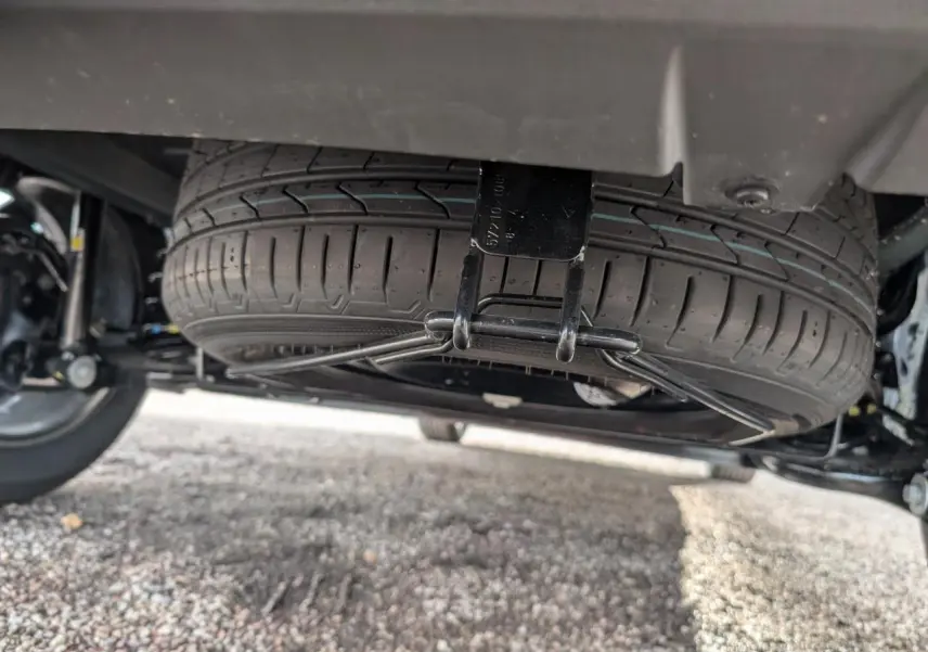 Gros plan sous le véhicule montrant la roue de secours suspendue du Dacia Jogger 2025, détail mécanique visible.