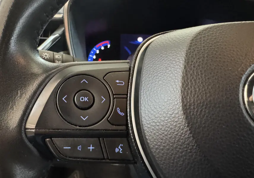 Gros plan sur les commandes multifonctions du volant cuir noir de la Toyota Corolla Hybride 122h Collection 2021.