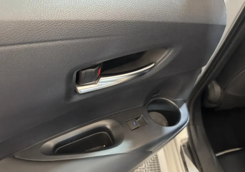Poignée intérieure chromée et commande de fenêtre sur la portière arrière droite d'une Toyota Corolla gris clair hybride 2021.