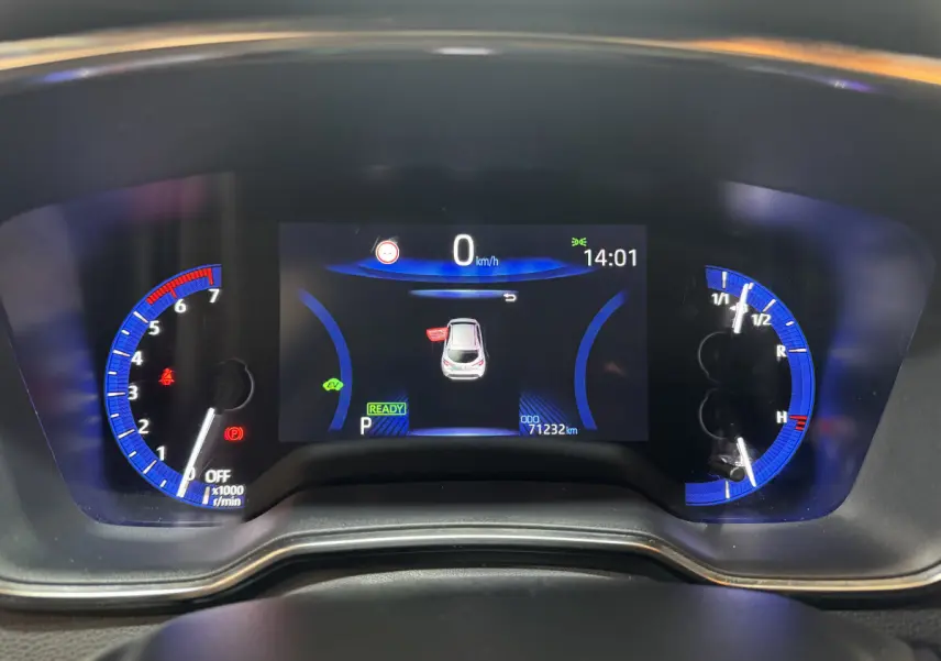 Tableau de bord numérique de Toyota Corolla Hybride 122h gris clair, affichage central avec compteurs bleus et informations de conduite.