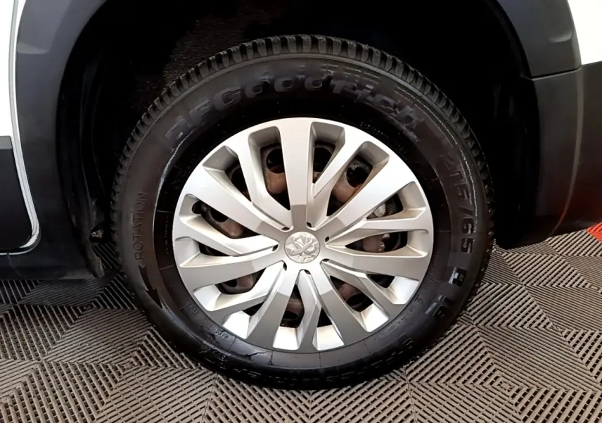 Gros plan sur la roue avant droite du Peugeot Rifter blanc, avec jante alliage et logo Peugeot central.