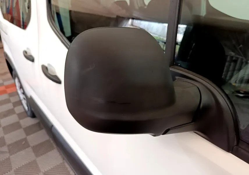 Gros plan sur le rétroviseur noir côté conducteur du Peugeot Rifter blanc, vue latérale avant gauche.