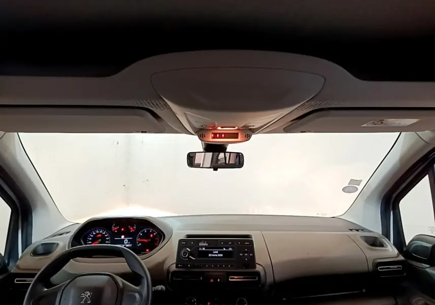 Vue intérieure avant du Peugeot Rifter 2019, tableau de bord beige avec volant noir et écran central allumé.