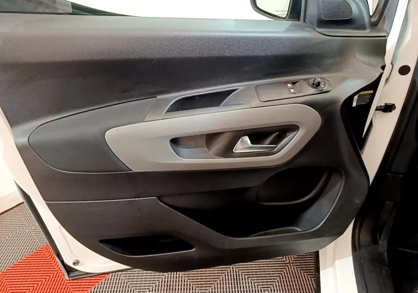 Vue rapprochée de la porte avant gauche blanche du Peugeot Rifter 2019, avec commandes électriques et poignée grise.