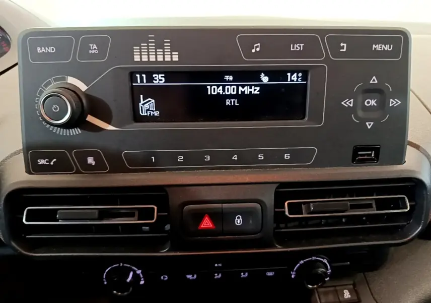 Détail du tableau de bord du Peugeot Rifter 2019 avec écran radio, commandes et aérateurs noirs horizontaux.