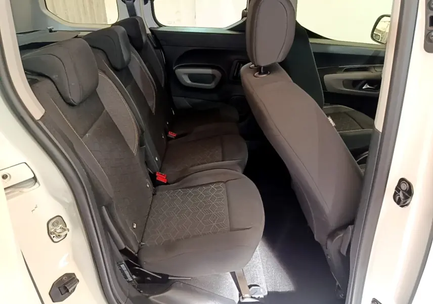 Vue intérieure côté gauche montrant la banquette arrière noire du Peugeot Rifter blanc, porte arrière ouverte.