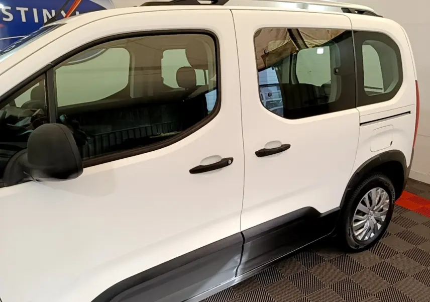 Vue latérale droite du Peugeot Rifter blanc avec protections noires sur les bas de caisse et jantes argentées.