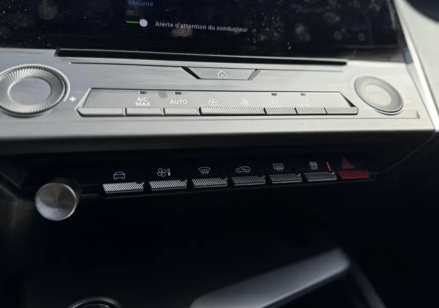 Gros plan sur la console centrale de la Peugeot 308 SW 2025, montrant les commandes climatisation et fonctions assistées.