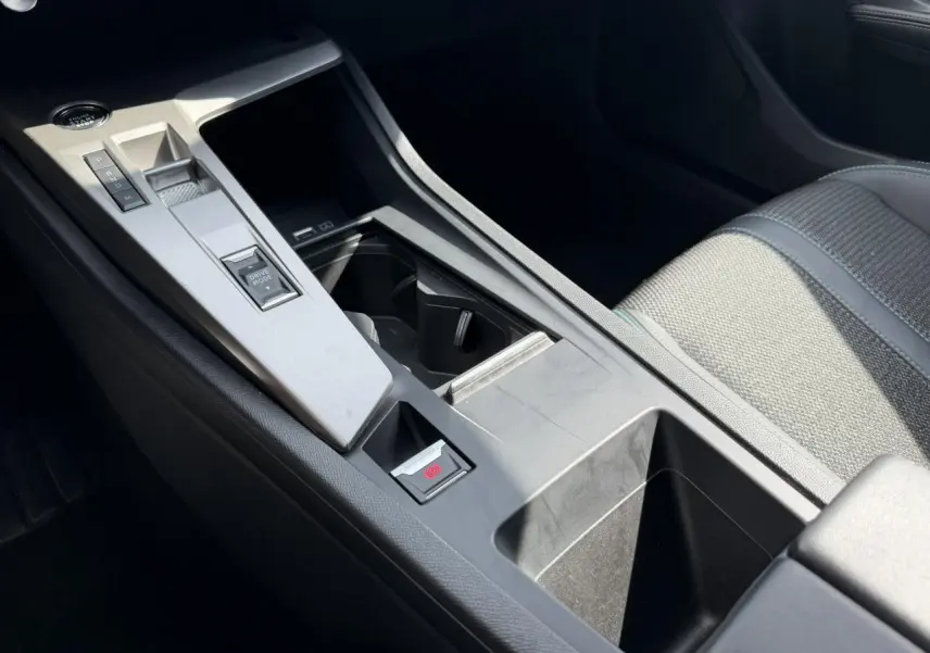 Vue rapprochée de la console centrale grise du Peugeot 308 SW 2025 avec levier de vitesses automatique et accoudoir tissu gris.