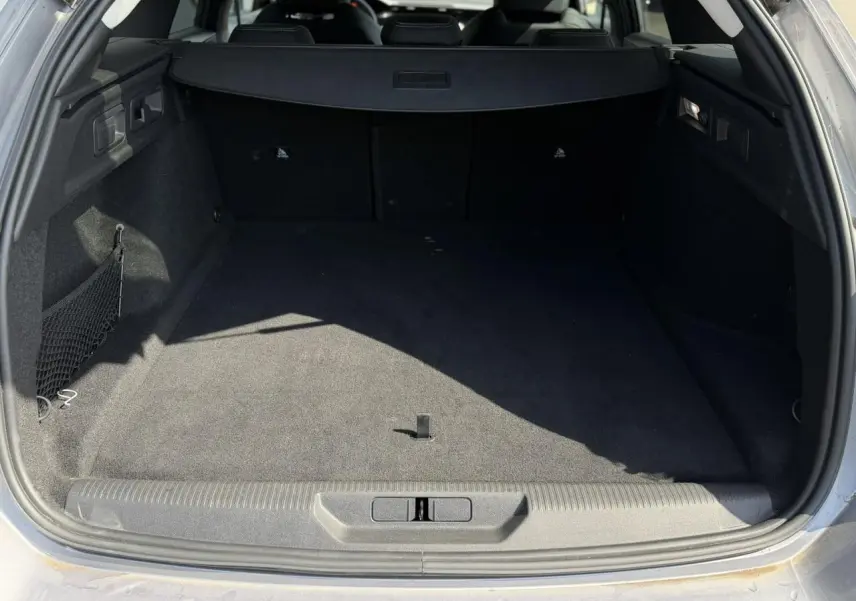 Coffre ouvert d’un Peugeot 308 SW gris Artense, montrant l’espace de chargement vide et la moquette noire.
