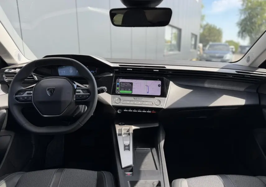 Vue intérieure avant du Peugeot 308 SW 2025 avec tableau de bord moderne et écran tactile central lumineux.