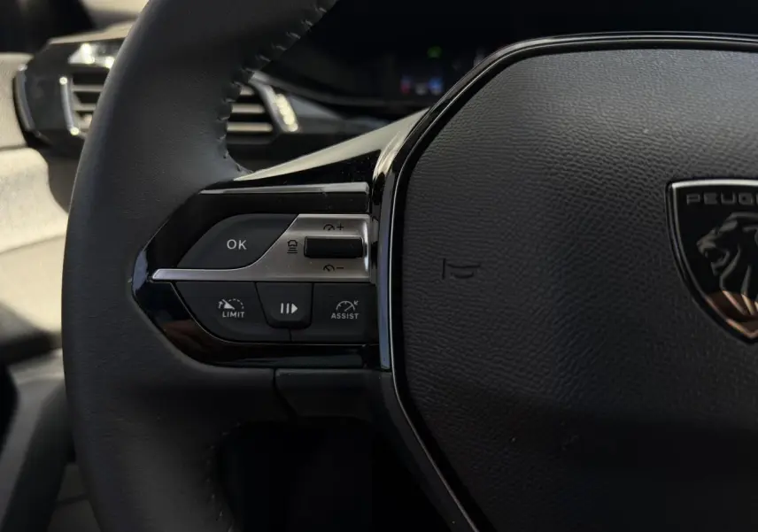 Gros plan sur le volant noir de la Peugeot 308 SW 2025, avec commandes du régulateur adaptatif visibles à gauche.