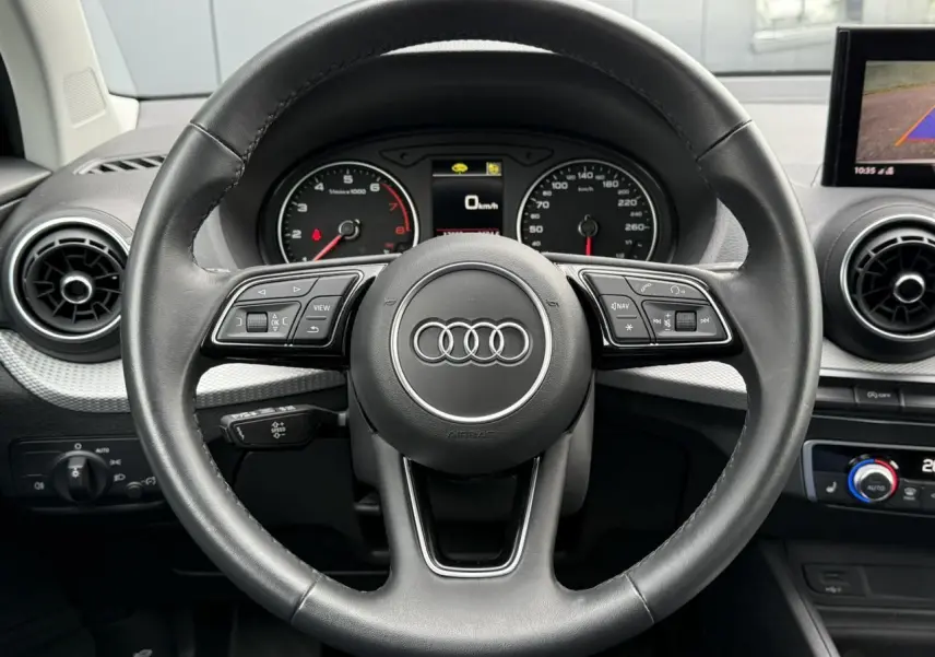 Vue rapprochée du volant en cuir noir avec commandes intégrées de l'Audi Q2 35 TFSI 150 S-Tronic S-Line 2023.