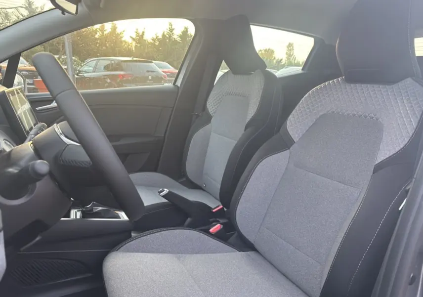 Intérieur de la Renault Clio 2025, vue côté gauche sur les sièges avant gris avec surpiqûres et volant.