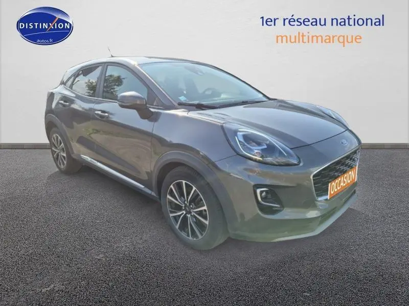 Ford Puma gris métallisé vu en 3/4 avant droit avec jantes alliage et calandre distinctive sur fond neutre.