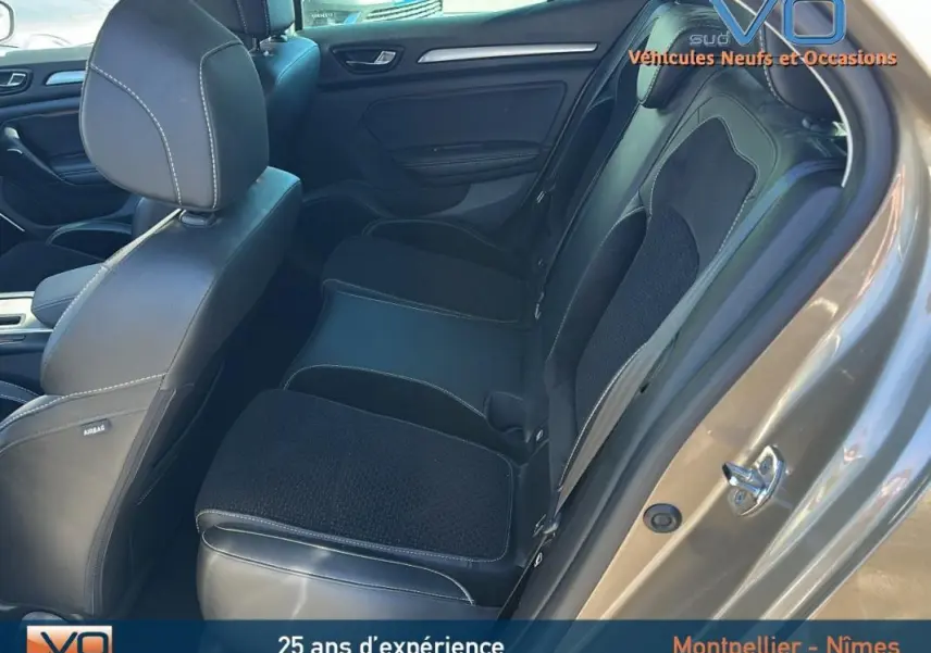 Vue intérieure côté arrière droit de la Renault Mégane IV beige, montrant les sièges en cuir et tissu noir.